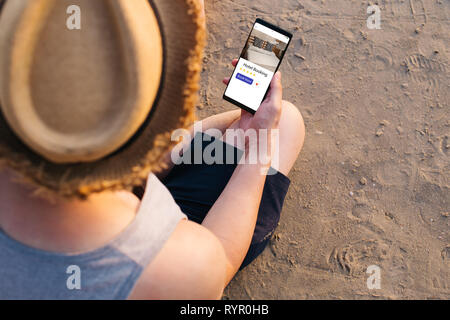 Close-up of young male traveler using mobile phone to book and reserve hotels online via app and website - summer holiday vacation booking concept Stock Photo
