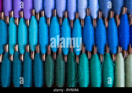 Image of three rows of colorful bobbin threads, stitching or sewing of blue, dark green, beige and violet colors Stock Photo