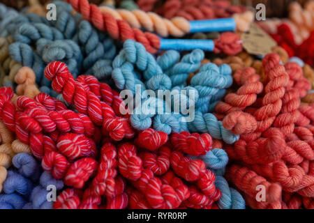 A pile of natural knitting yarn of red, blue and brown colors is ready for work. Textile pattern or knitting background Stock Photo