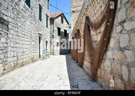 Street shot in old town Hvar, Croatia with fishing nets hanging from street wall Stock Photo