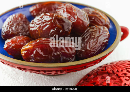 Dates in a bowl, close up on a kitchen table with white background Stock Photo
