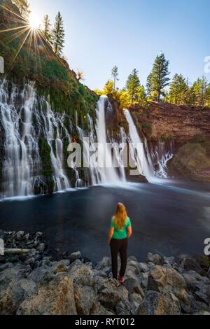 Young woman standing at a waterfall, McArthur-Burney Falls Memorial State Park, California, USA
