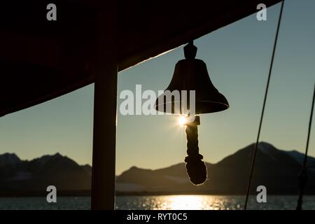 Ship's bell of a sailing ship, Silhouette in front of sun, Spitsbergen, Svalbard, Norway Stock Photo