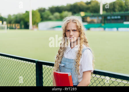 young girl blonde with blue eyes puffed up her lips and made an angry face Stock Photo