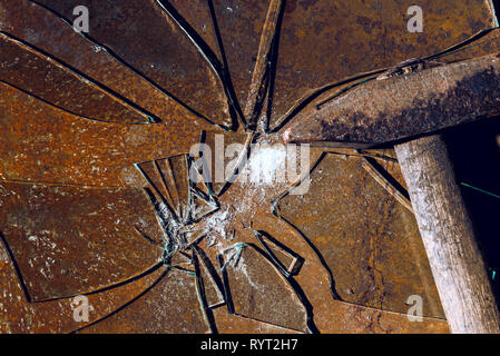 broken glass to pieces on a rusty metal sheet. next to it is an old hammer with a wooden handle. texture. background