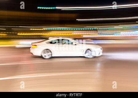 Car rolling at full speed through the city at night, image of panning, with defocused background lights. Stock Photo