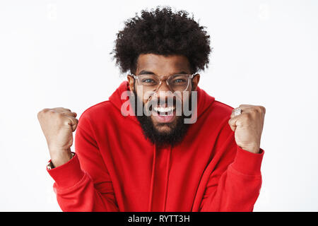 Thrilled and excited guy clenching raised fists in joy yelling from amazement and happiness as triumphing delighted and satisfied with success Stock Photo