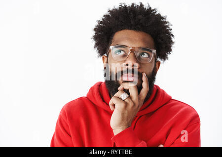 Close-up shot of thoughtful african american man rubbing beard and looking at upper left corner focused, thinking, taking important decision, making Stock Photo
