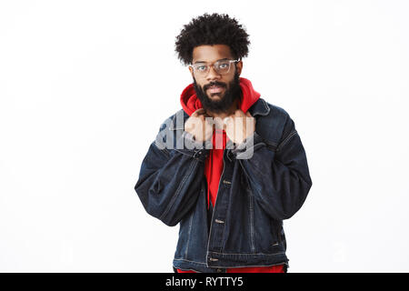 Guy checking outfit in mirror looking lit and stylish smiling at camera self-assured as getting ready to date standing in denim jacket touching collar Stock Photo