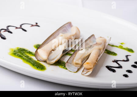 knives cooked on the grill with green sauce Stock Photo