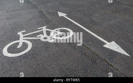 Cycle path indicated by painted white bike on tarmac with arrow indicating both directions. Stock Photo