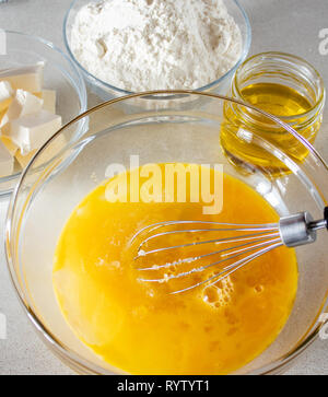 Ingredients for cooking. Eggs in a bowl with a whisk for beating. Close-up of eggs. Stock Photo