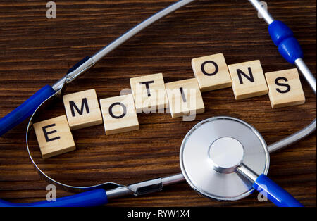 'Emotions' word written on wooden blocks between stethoscope - diagnosis Stock Photo