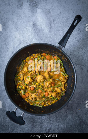 Top view of vegetable korma curry with korma curry paste sauce in a cooking pan. Light grey background. Distant view of Indian korma curry. Stock Photo