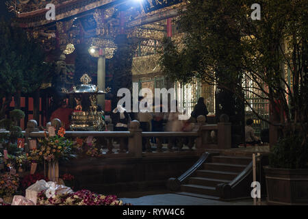 Lungshan Temple, historic Buddhist and Taoist temple, worshippers gather around the altar, seen at night, Wanhua District, Taipei City, Taiwan Stock Photo