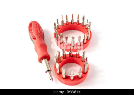 Screwdriver with red handle, set of screwdriver heads (bits) for tools, close-up, selective focus, on a white background. Stock Photo