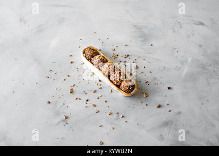 Raw bliss balls with chopped hazelnuts in an oval bowl on the textured background Stock Photo