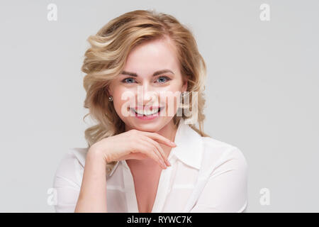 Image of happy curly woman in white shirt in studio. Stock Photo