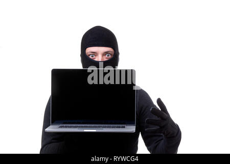 Thief man in black mask with laptop with blank screen in hands. Stock Photo