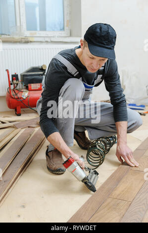 Building home using an air hammer to nail wooden beams framework of ...