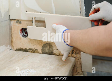 A worker installs tile with holes for the outlet box. Stock Photo