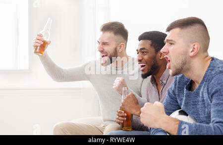 Friends cheering for favourite team at home Stock Photo