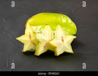 Ripe carambola fruit with three slices on dark background Stock Photo