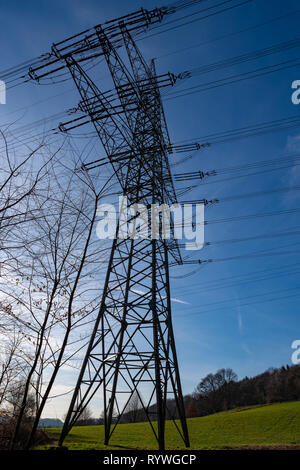 Electricity pylon against a blue sky in the evening sun, photographed from below Stock Photo