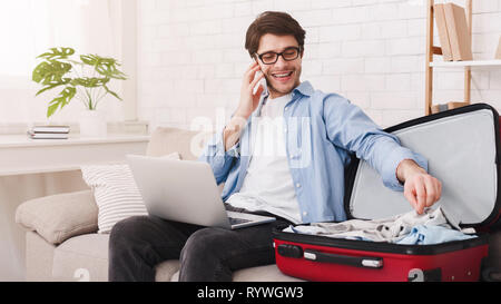 Man talking on phone and packing clothes Stock Photo