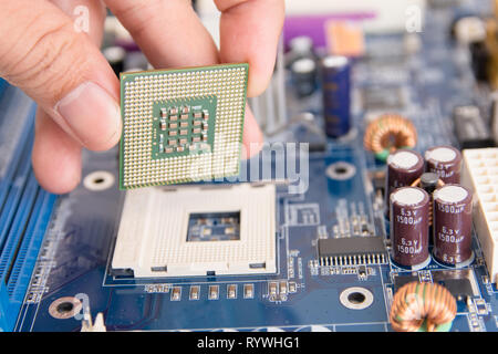 Technician installing CPU chip microprocessor to socket on motherboard Stock Photo