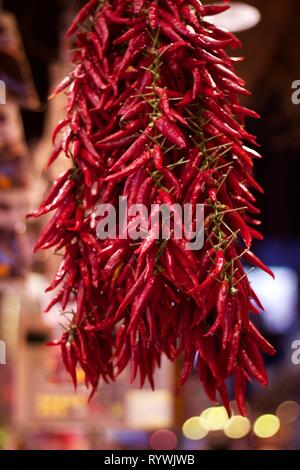 Chillies hanging in market stall Stock Photo