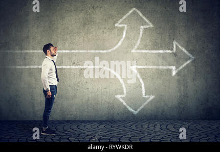 Confident businessman looking into the future as a crossroad arrows split in three different ways. Choosing the right way making difficult decision co Stock Photo