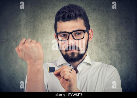Futuristic technology with biometric implant concept. Young man holding a microchip willing to implant it under the skin Stock Photo