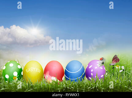 Easter eggs, dyed, with a pattern on the background of a sunny sky in the grass Stock Photo