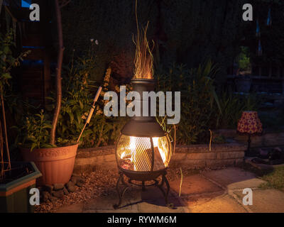 Sparks fire out of the top of a chiminea on a summers evening Stock Photo