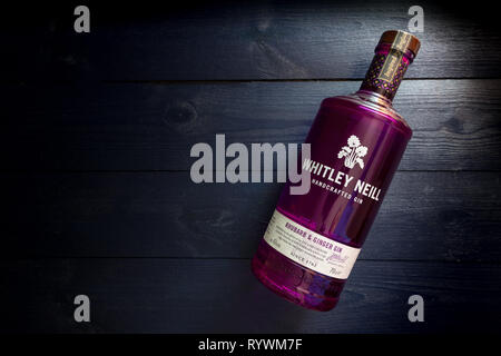 LONDON - MARCH 13, 2019: Whitley Neill Rhubarb Ginger Gin in purple glass bottle on dark wood background Stock Photo