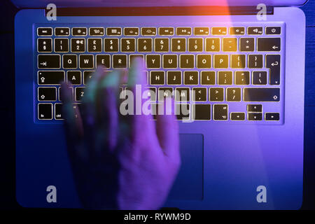 Man typing on laptop computer keyboard at night online cyber crime hacker concept Stock Photo