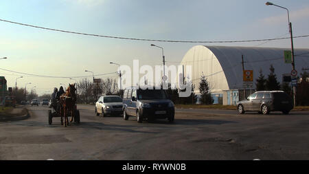 Ploiesti, Romania - December 16, 2016: People in a horse drawn carriage go through traffic between cars on a national road, near Ploiesti, Romania. Stock Photo