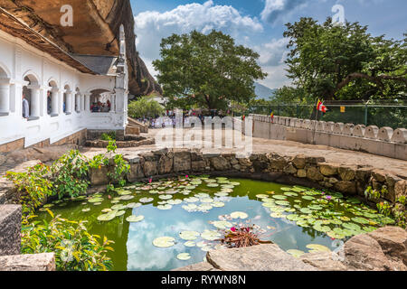 A school party gather in the courtyard waiting to enter the most impressive of Sri Lanka's Cave Temples, the richly decorated five shrines of 'Dambull Stock Photo