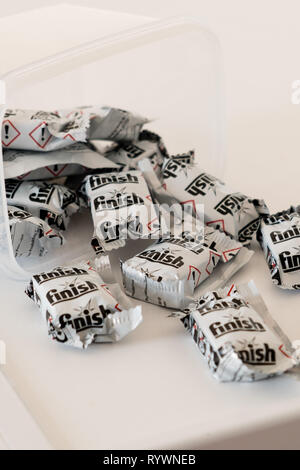 Largs, Scotland, UK - March 15, 2019: Finish Branded Dishwasher Tablets spilling out of a plastic Box onto a white kitchen appliance. Stock Photo