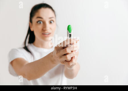 Smiling young woman looking on pregnancy test at studio. Stock Photo
