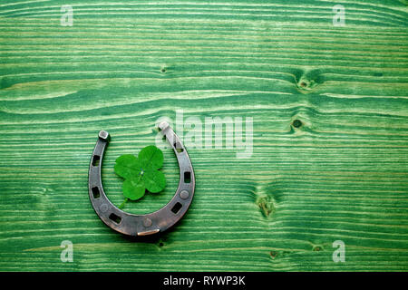 four-leaved clover and a horse shoe on wooden background. St. Patrick's day Stock Photo