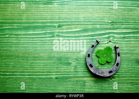 four-leaved clover and a horse shoe on wooden background. St. Patrick's day Stock Photo