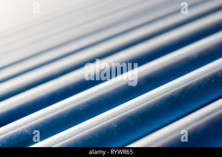 Macro shot of the grey silver glass tubes of a solar water heater mounted on the roofs of a house to save power and use renewable energy and green ene Stock Photo