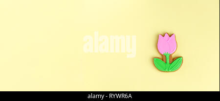 Gingerbread in the form of a tulip on a yellow background. Spring, Easter, minimalism Stock Photo