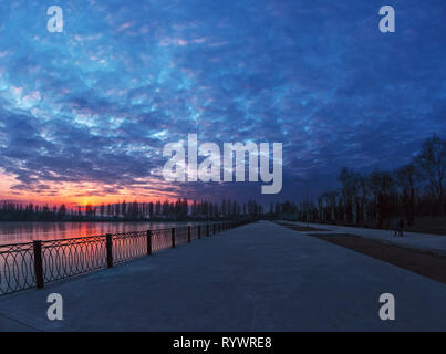 Fantastic bright cloudy sunset over the lake and the road. Winter landscape in the city Stock Photo