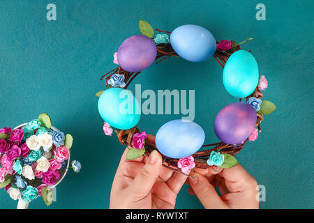 Diy Easter wreath of twigs, painted eggs and artificial flowers on a green background. Gift idea, decor Spring, Easter. Step by step. Top view. Proces Stock Photo