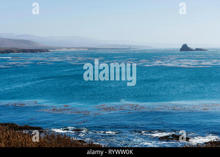 Looking out over blue ocean and gray sky, waves breaking on rocks below. Stock Photo