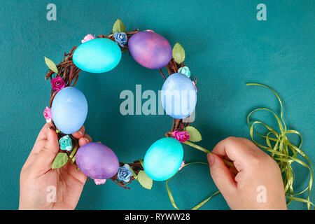 Diy Easter wreath of twigs, painted eggs and artificial flowers on a green background. Gift idea, decor Spring, Easter. Step by step. Top view. Proces Stock Photo