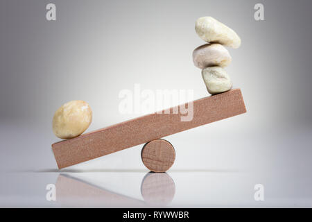 Pebble Stones Balancing On Wooden Seesaw Over The White Background Stock Photo
